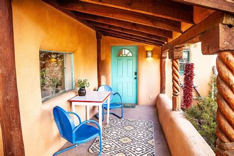 A Patio With Blue Chairs And A Table On The Side Walk Next To A Green Door