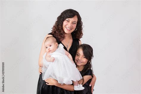 Beautiful Latina Mom With Her Two Pretty Daughters Standing And Hugging Smiling At The Camera