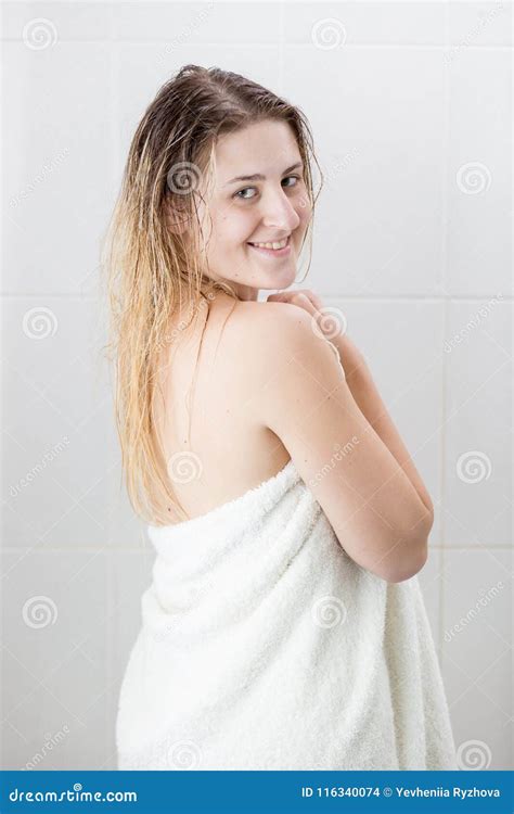 Portrait Of Smiling Blonde Woman In White Towel After Having Shower Looking In Camera Stock