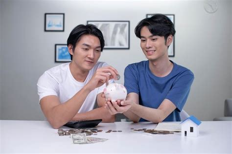 Jovem casal gay asiático feliz economizando dinheiro para comprar uma casa casal de homens lgbt