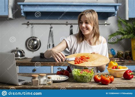 Young Girl Prepares A Vegetarian Salad In The Kitchen She Adds Sliced