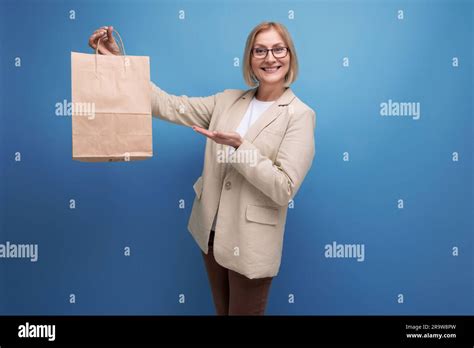 Joyful S Mature Woman In Jacket With S Kraft Shopping Bag On Studio Background With Copy Space