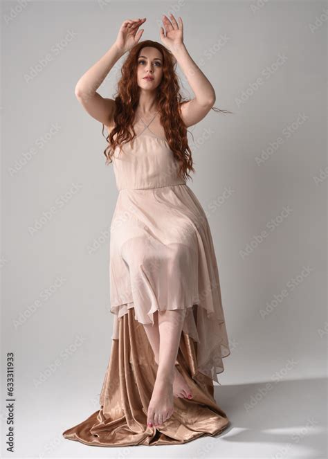 Full Length Portrait Of Beautiful Female Model With Long Brunette Hair Wearing A Creamy Pink