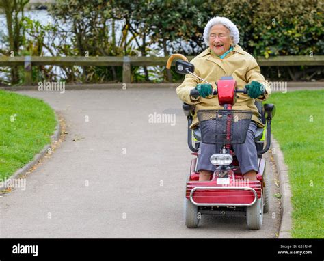 Happy Elderly Lady Riding A Mobility Scooter In A Park Stock Photo Alamy