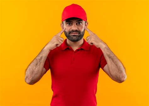 Free Photo Bearded Delivery Man In Red Uniform And Cap Pointing With