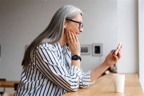 Smiling White Haired Mature Woman Drinking Coffee And Using Cellphone Stock Image Image Of