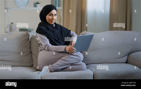 Attractive Young Muslim Woman Wear Hijab Sit On Cozy Sofa In Living