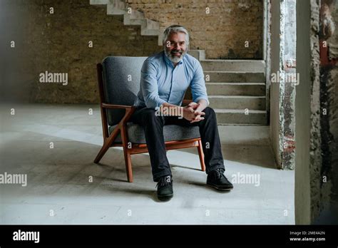 Happy Mature Architect Sitting In Chair At Construction Site Stock