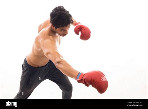 Man Throwing Punch In The Air While Wearing Boxing Gloves In Front Of A