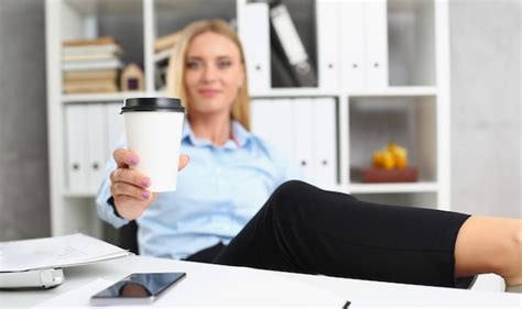 Eine blonde frau hebt eine heiße tasse kaffee trinkt eine pause von der arbeit und jubelt
