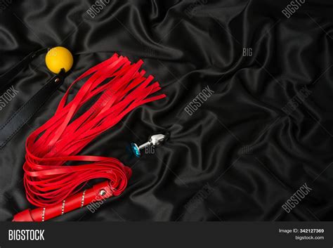 Red Whip Gag Anal Plug On A Black Silk Background Accessories For