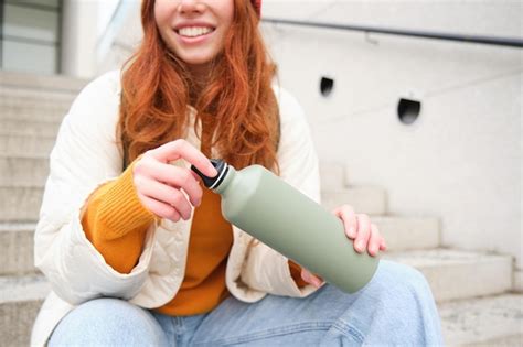 Premium Photo Smiling Traveler Redhead Girl Tourist Sits On Stairs With Flask Drinks Hot