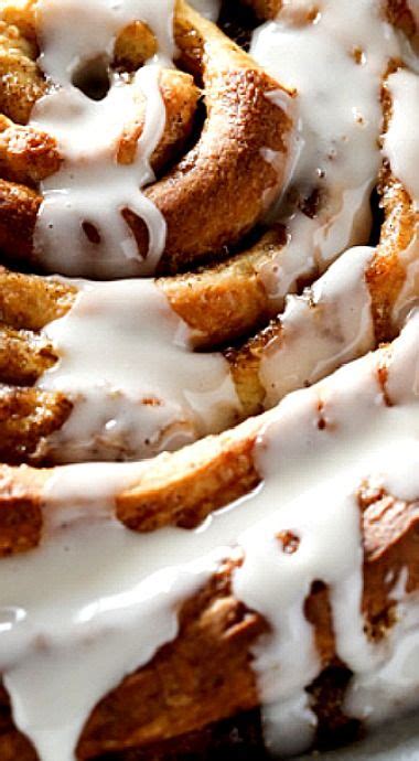 Cinnamon Rolls With Icing Sitting On Top Of A White Plate