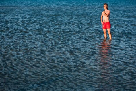 Premium Photo Shirtless Man Wearing Red Shorts Standing In Rippled Sea