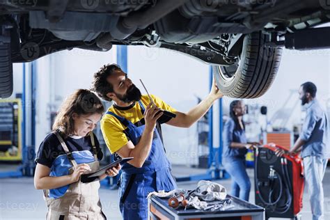 Technicians collaborating on servicing broken vehicle, checking for