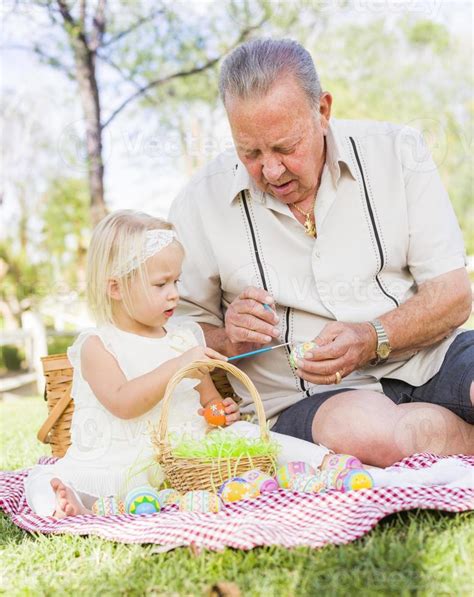 grand père et petite fille colorant des oeufs de pâques sur une