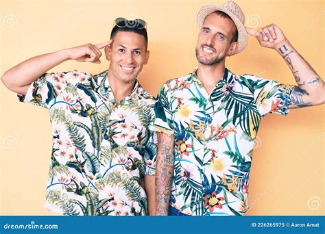 Joven Pareja Gay De Dos Hombres Con Sombrero De Verano Y Camisa Hawaiana Sonriendo Apuntando A