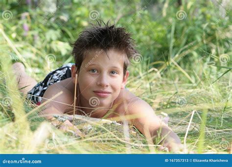 Een Brunette Jongen Ligt In De Zomer In Het Zonneschijn In Het Gras Russisch Stock Afbeelding