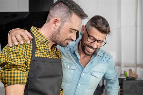 Feliz pareja gay hipster enamorada parada en la cocina Están cocinando la cena juntos en casa