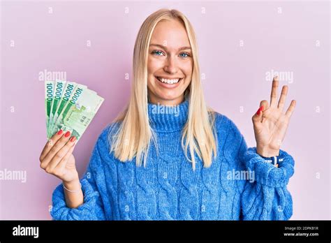 Une jeune fille blonde tenant sud coréenne a gagné des billets de banque faisant signe ok