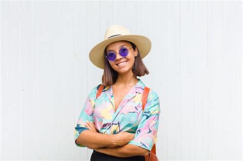 Mujer latina sonriendo a la cámara con los brazos cruzados y una expresión feliz confiada y