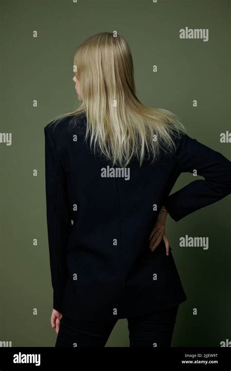 Elegant Strict Blonde Girl Turns Her Back To The Camera Looks Away Posing On A Green Background