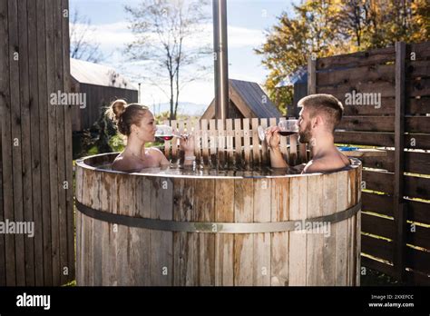 Romantic Couple Relaxing And Enjoying The Soothing Warm Waters Of An Outdoor Hot Tub Toasting