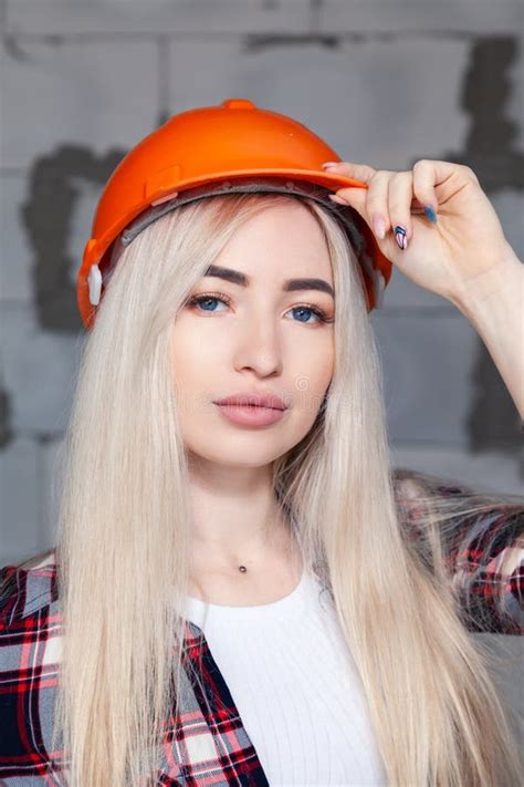 Belle Fille La Blonde D Agent De Ma Trise De Concepteur Dans Un Casque Orange De Construction Et