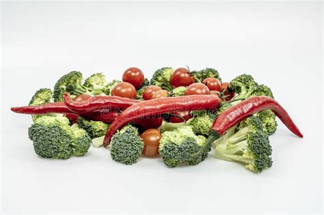 Red Hot Chili Peppers Ripe Cherry Tomatoes And Raw Broccoli Stalks On A Plain White Surface