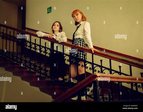 Two Female Uniformed Students One Blonde And The Other A Red Haired Asian Are Seen Standing On