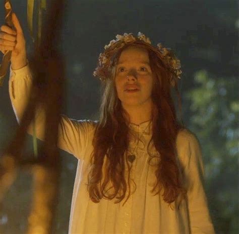 A Woman With Long Hair Wearing A White Dress And Holding A Flower In