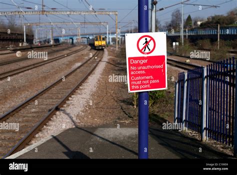 Danger Sign On Railway Station Platform With Train Approaching Stock