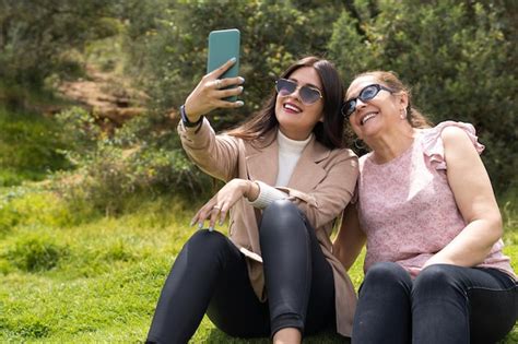 Uma Jovem Adulta Latina E Sua M E Sentada Na Grama Est O Tirando Uma Selfie Foto Premium