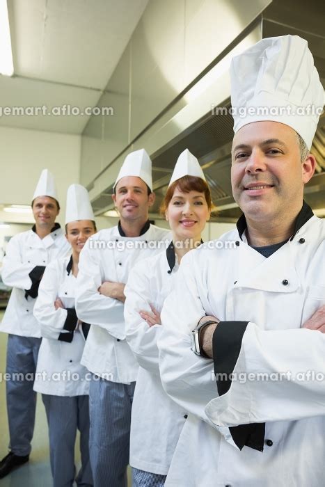 Team Of Happy Chefs Smiling At The Camera In A Kitchen Wearing Uniforms