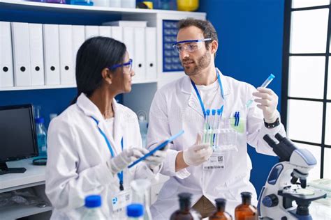 Man And Woman Scientists Using Touchpad Holding Test Tubes At