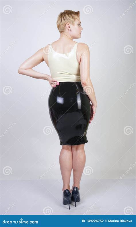 Hot Short Hair Blonde Girl With Curvy Body Wearing Latex Rubber Dress On White Studio Background