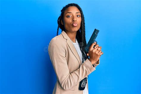 African American Police Woman Holding Gun Looking At The Camera Blowing