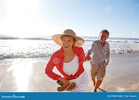 Full Of Vitality A Mature Couple Enjoying A Late Afternoon Walk On The Beach Stock Photo
