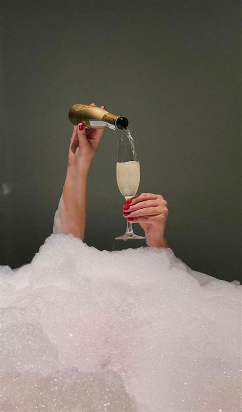 A Woman Holding A Champagne Glass In Her Hand And Pouring It Into A