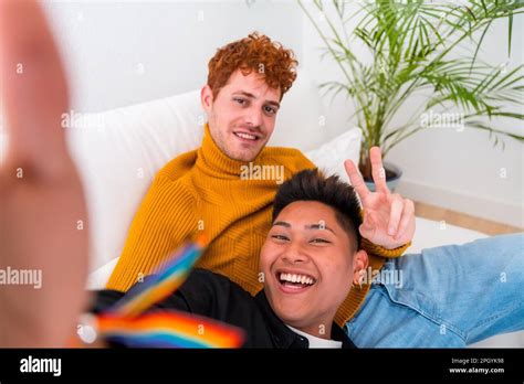 Beautiful Gay Couple Being Romantic Indoors At Home On The Sofa Gay Couple Taking Selfie Lgbt