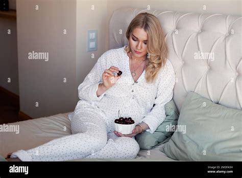 Pregnant Woman Sitting On Bed And Eating Cherry Berries Beautiful Pregnancy Blonde Model In