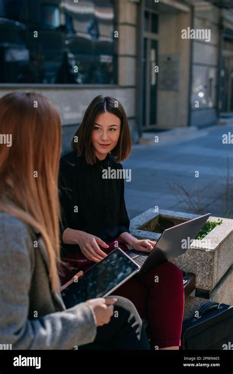 Lovely Short Haired Brunette Businesswoman Listening To Her Blonde Colleague Talking Working