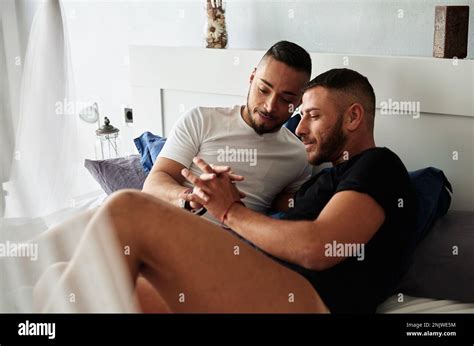 Male Gay Couple Holding Hands While Lying In Bed Together Stock Photo Alamy