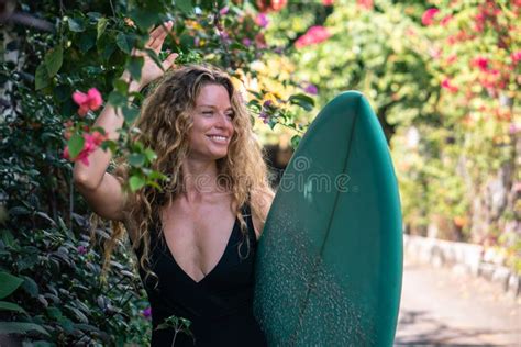 Retrato De Una Joven Con Pelo Rubio Y Largo Rizado En Bikini Con Tabla De Surf Azul En La Calle