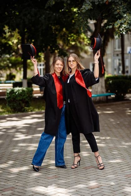 Premium Photo Two Women In Graduation Caps And Gowns Pose For A Picture