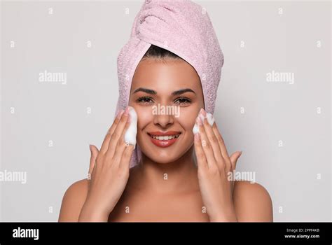 Beautiful woman applying facial cleansing foam on white background ...