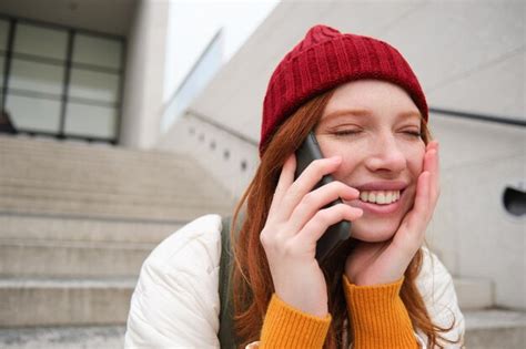 Premium Photo Young Stylish Redhead Girl In Red Hat Sits On Street