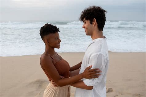 Lindo casal mostrando carinho na praia perto do mar Foto Grátis