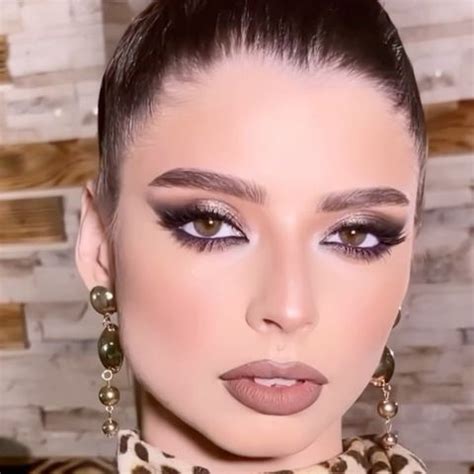 A Woman With Dark Makeup And Leopard Print Scarf Around Her Neck Is