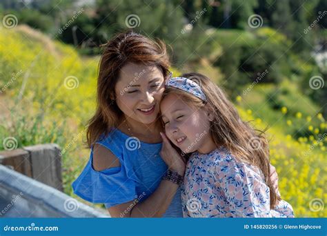 M E E Filha De Latina Que Sorriem E Que Riem Em Um Monte Na Frente Das Flores Amarelas Foto De